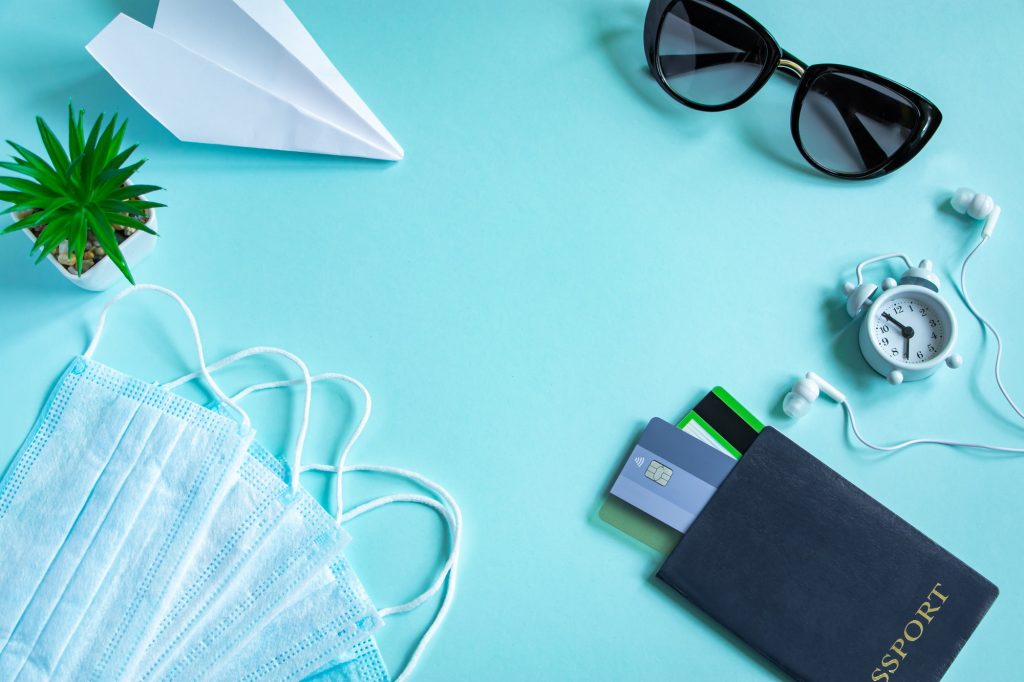 Passport, medical mask and sunglasses on a blue background.